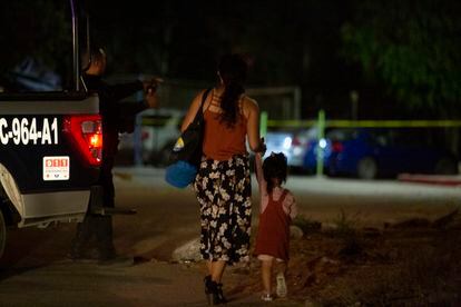 Una mujer y una niña pasan frente a la policía municipal luego de una serie de ataques en la Zona Este de Tijuana, Baja California. 