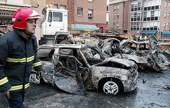 Un bombero, junto a algunos de los vehículos que resultaron calcinados en el centro de Estella.