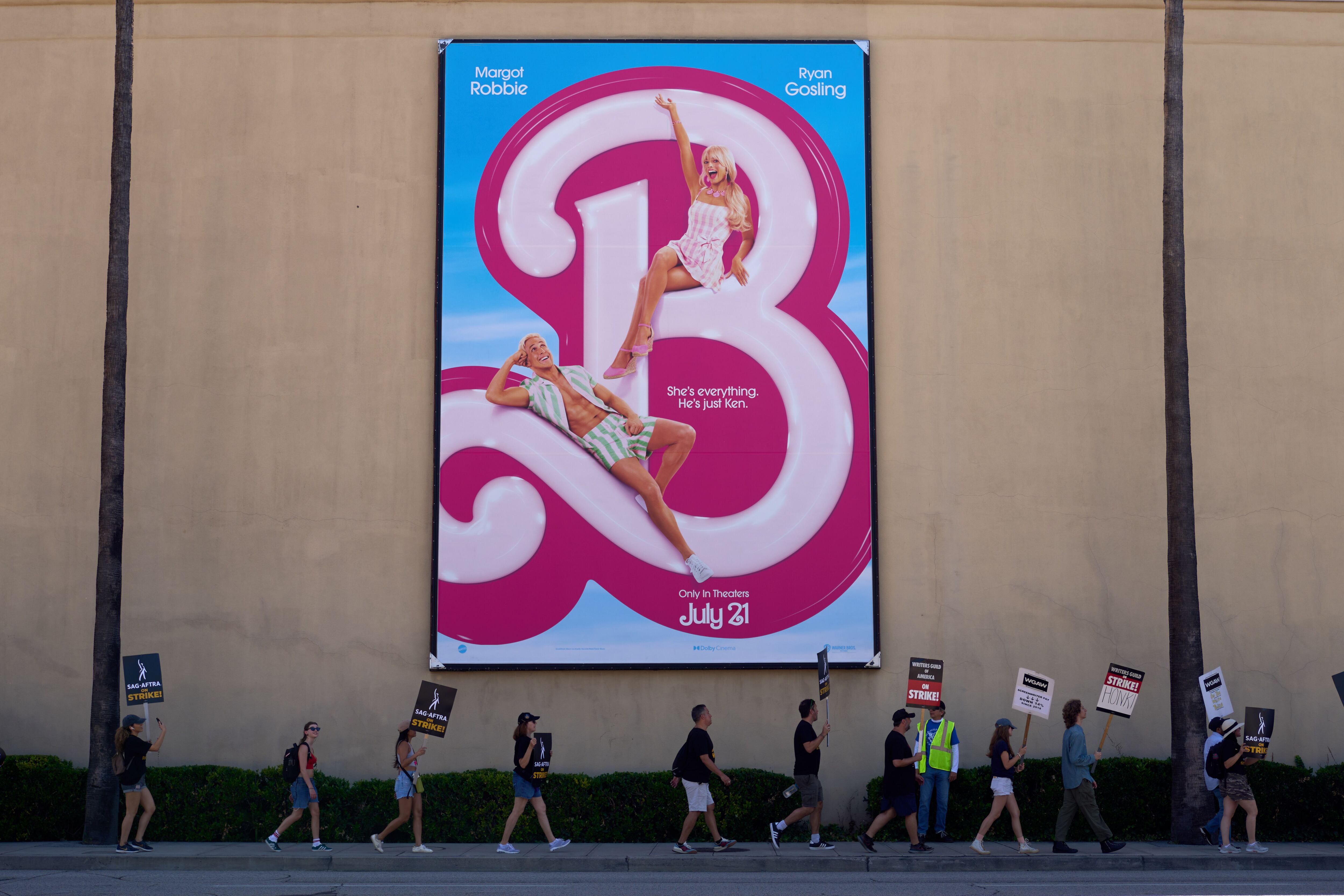 Miembros de los sindicatos de actores y guionistas protestan en piquetes frente a un enorme cartel de la película 'Barbie' en los estudios de Warner Brothers en Burbank, al norte de Los Ángeles, California, en el primer día de huelga de actores.