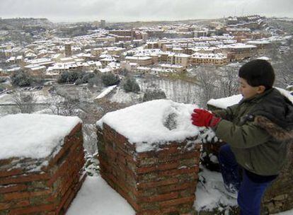 Un niño juega con la nieve junto a las murallas de Segovia tras la nevada caída esta noche en la provincia.