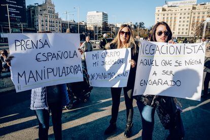 Tres mujeres sostienen diferentes pancartas durante una manifestación negacionista, el 11 de diciembre de 2021 en Madrid.