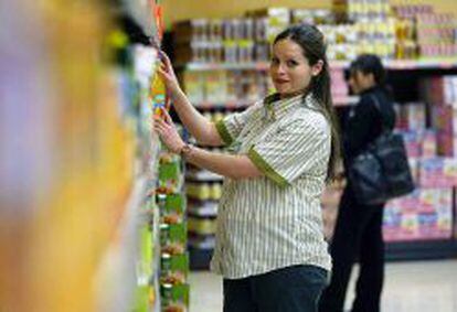 Una empleada embarazada de la cadena de supermercados Mercadona coloca art&iacute;culos en una estanter&iacute;a. 