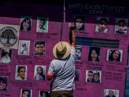 Un hombre escribe los nombres de desaparecidos junto a sus fotografías, en Ciudad de México, en mayo de 2022.
