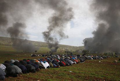 Palestinos participan en las oraciones del viernes entre el humo de los neumáticos quemados durante una protesta contra los asentamientos judíos, en la aldea de al-Mughayyir, cerca de Ramallah, en la Cisjordania ocupada, el 1 de febrero de 2019.