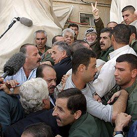 Yasir Arafat saluda a los palestinos que acudieron ayer a defenderle en su cuartel general en Ramala.