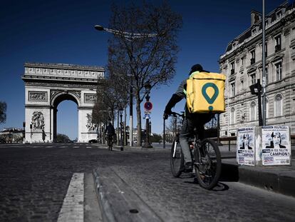 Un repartidor atraviesa unos Campos Elíseos casi vacíos, en París.