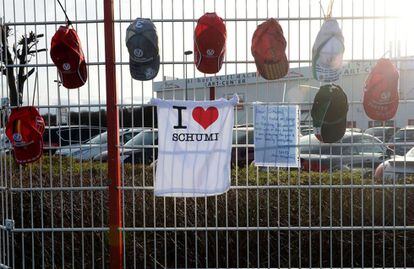 Camisetas y gorras con mensajes de ánimo para Schumacher cuelgan de una valla en el Hospital de Grenoble
