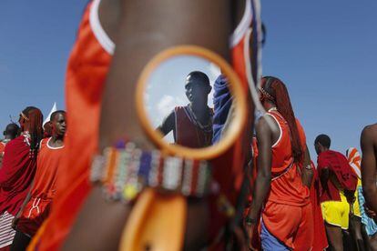 Un masai se refleja en un espejo usado por otro hombre, mientras se preparan para competir.