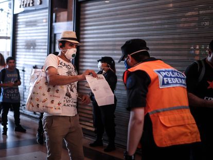 Un hombre le muestra a la policía un certificado para poder circular libremente en Buenos Aires.