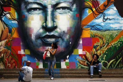 El proyecto urbanístico favorito del difunto presidente recibe su nombre -'Ciudad Caribia'- por los caribes indígenas del país. En la foto, varias personas permanecen delante de un mural con el rostro de Hugo Chávez.