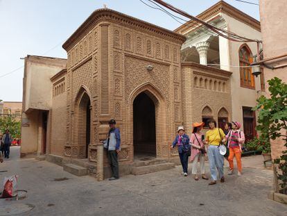 Un grupo de turistas chinos pasa junto a una mezquita clausurada en la ciudad antigua de Kashgar.