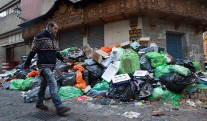 Un hombre pasa junto a la basura acumulada en una calle del centro de Granada.