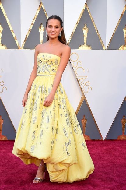 Alicia Vikander, de 27 años, ganadora del Oscar como actriz de reparto por su papel en la película ‘La chica danesa’ se decantó por un vestido de la firma francesa Louis Vuitton, de la que es imagen. Sus últimas apariciones en la alfombra roja han calado entre los críticos de moda que han aplaudido su estilo sobrio y elegante. Sus preferencias son sencillas y refinadas, aunque suele elegir atuendos que tengan un detalle como protagonista, ya sea la espalda al aire, tejidos plisados, brillantes o de cuero.