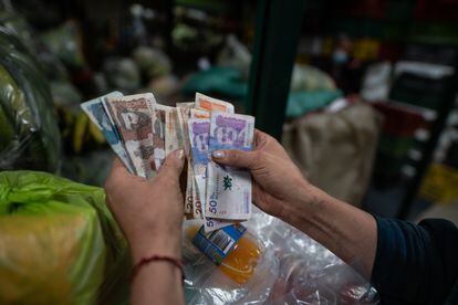 Una vendedora cuenta dinero en un mercado en Bogotá.