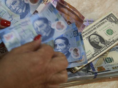 Una mujer cuenta billetes de pesos mexicanos en una casa de cambio monetario.