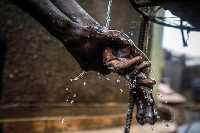 Un hombre lava sus manos en agua del grifo en un punto de recogida de agua en Kibera, en los suburbios de Nairobi (Kenia).