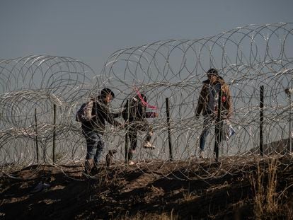 Tres migrantes cruzan el alambrado en la frontera entre México y EE UU en Ciudad Juárezm el pasado 10 de mayo.