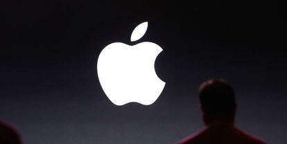 Una persona junto a un logo de Apple.