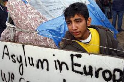 Un inmigrante ilegal tras un cartel en el que pide asilo en Europa. EFE/Archivo