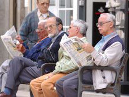 Varios pensionistas jubilados leen el periódico.
