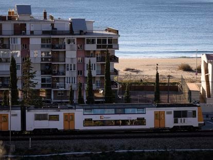 Un tren de Rodalies Renfe circula a la altura de la playa de Castelldefels, en Barcelona.