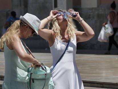 Dos turistas que visitan Valencia alivian el calor con agua. 