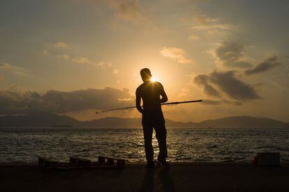 Un pescador en el muelle del puerto de Victoria en Hong Kong.
