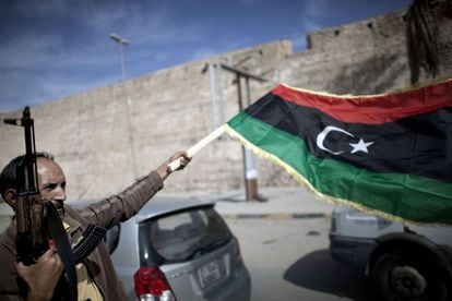 Un combatiente del CNT agita la nueva bandera libia en Trípoli, tras conocerse la captura de Gadafi.