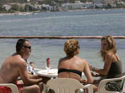 Unos turistas conversan en una terraza en la playa ibicenca de Talamanca. 