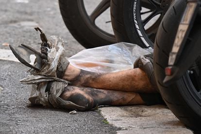 Detalle de los pies de un vagabundo que descansa en un aparcamiento de motos, en el centro de Roma (Italia) este miércoles. 
