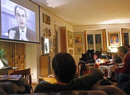 Joaquín Sabina (al fondo, segundo por la izquierda) sigue en su casa el debate entre Zapatero y rajoy acompañado de unos amigos.