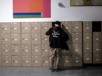 Un alumno saca los libros de texto de su taquilla en una biblioteca.