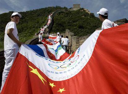 Voluntarios chinos sostienen una bandera formada con distintos escudos nacionales.