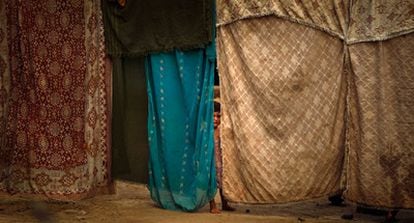 Una niña se esconde detrás de unas telas que hacen de muro de una casa improvisada en Adiel Khan, en las afueras de Peshawar.