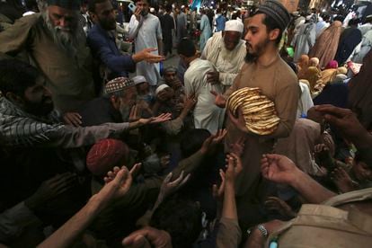 Un trabajador distribuye gratuitamente roti, pan tradicional, entre personas necesitadas en un restaurante en Peshawar, Pakistán.