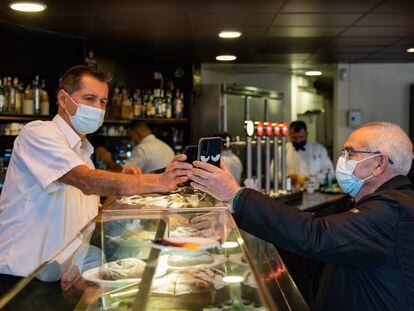 Un camarero escanea el código QR del certificado de vacunación de un cliente en el bar Zurich de la plaza de Cataluña de Barcelona, el día 3.