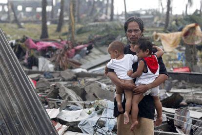 Un padre filipino y sus hijos esperan ayuda alimentaria fuera de su tienda de campaña en el súper tifón Yolanda que devastó la ciudad de Tacloban, provincia de Leyte,