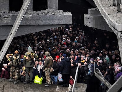 Ciudadanos ucranios intentan pasar por debajo de un puente destruido en Irpín, cerca de Kiev, el 5 de marzo