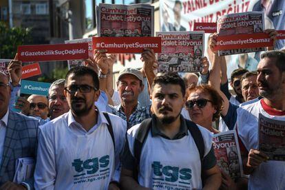 Compañeros de los periodistas detenidos y manifestantes sostienen copias del diario 'Cumhuriyet' el inicio del juicio contra 19 de sus empleados y directivos este lunes en Estambul.
