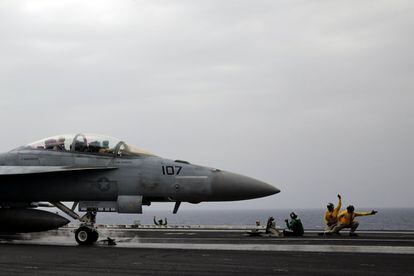 Oficiales de la Marina estadounidense (en chalecos amarillos), conocidos como "tiradores", señalan a un piloto de caza F / A-18 para un despegue seguro, a bordo del portaaviones Harry S. Truman del USS en el Mar Mediterráneo oriental.