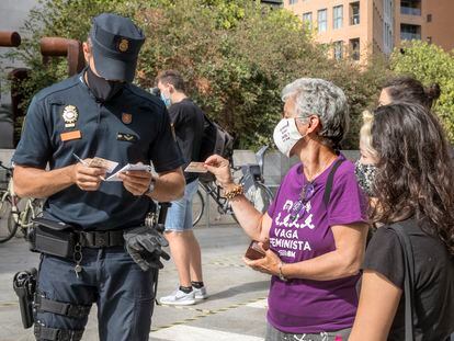 Un policía identifica, a las puertas de la Ciudad de la Justicia de València, a una participante en la concentración de apoyo a una de las feministas sancionadas por la huelga del 8M de 2018.