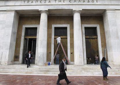 Varias personas pasan delante de la sede del Banco de Grecia. 
