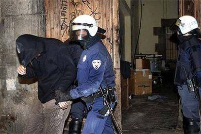 Un miembro de los antidisturbios de la Guardia Urbana se lleva a uno de los <i>okupas</i>.