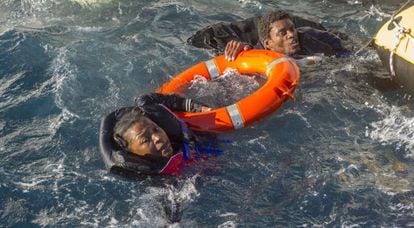 Dos inmigrantes que viajaban en las balsas hinchables son sacados del agua, a la que se lanzaron antes de ser rescatados.