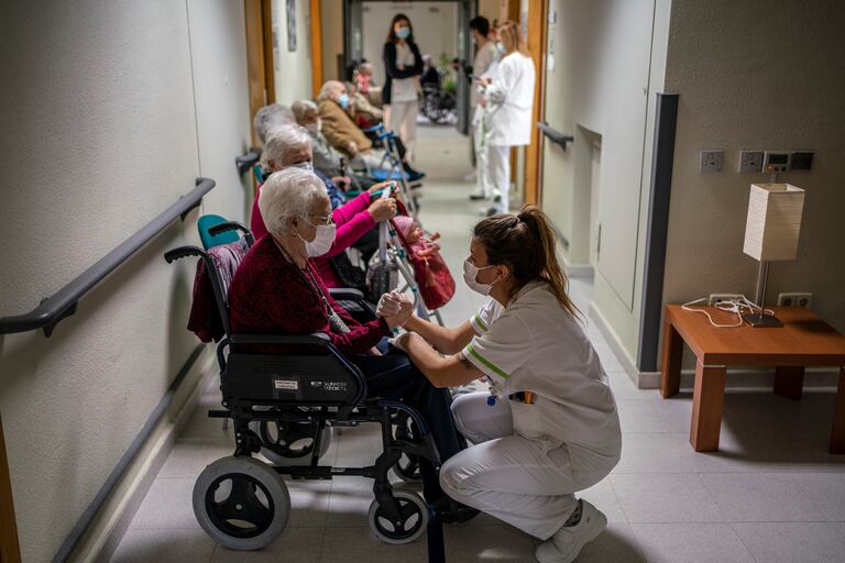 Ancianos de la residencia de mayores Domusvi de Leganés, en Madrid, esperan en un pasillo para recibir la vacuna.