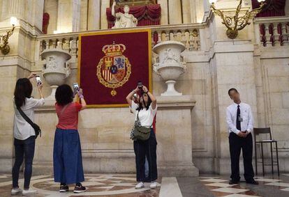 Un auxiliar de sala en el Palacio Real, junto a varias turistas.
 