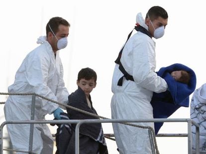 Dos hombres trasladan a un ni&ntilde;o y un beb&eacute; tras ser rescatados en Malta.
