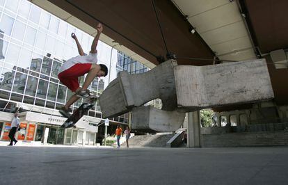Un adolescente hace piruetas con su patinete junto a la "Sirena varada" de Eduardo Chillida, en el Museo de Arte Público, situado en el paseo de la Castellana.