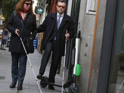 Dos personas ciegas sortean un patinete eléctrico en el centro de Madrid. En el vídeo, paseo con una persona ciega por la ciudad.