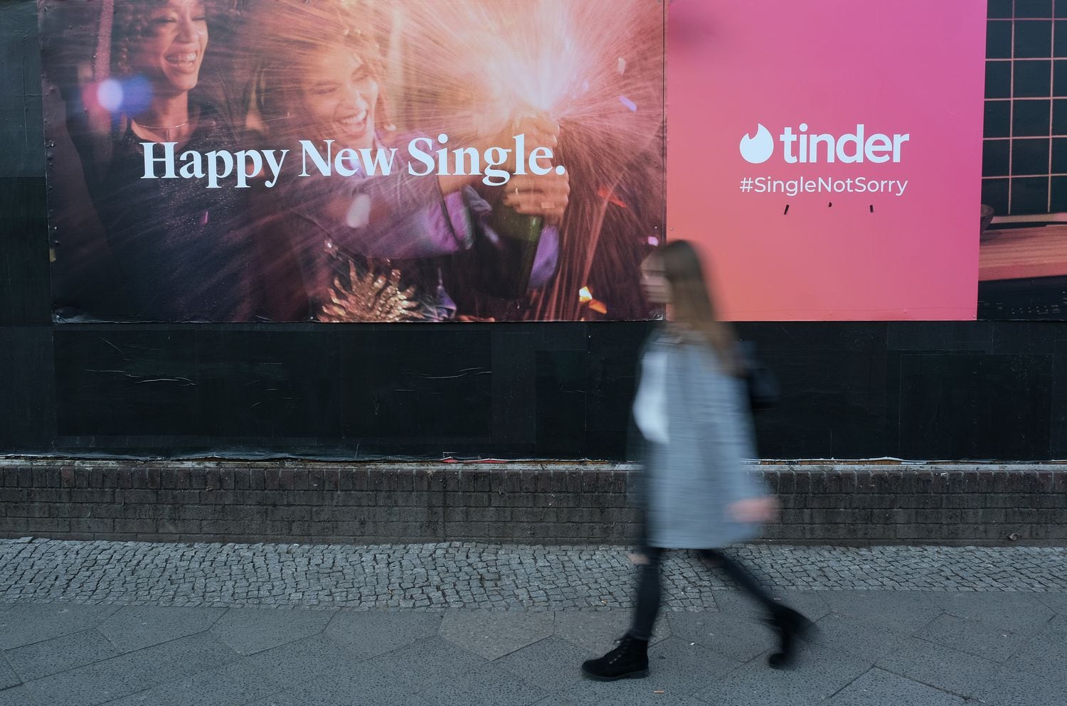 Una mujer pasa por delante de un anuncio de la aplicación de citas Tinder.
